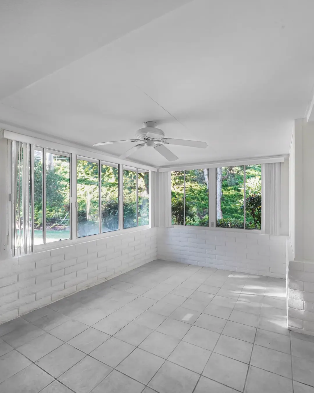 A sunroom with a tiled floor, large windows and a ceiling fan looking out on the yard, sunroom in Tampa