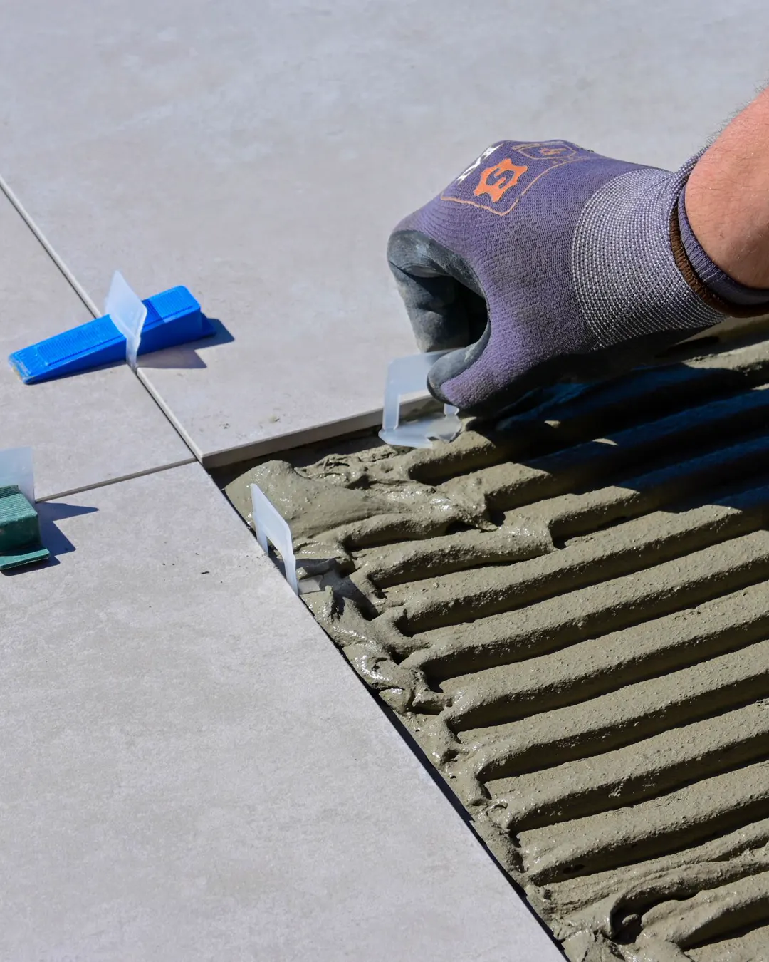 Large format floor tile being set in mortar with leveling clips, tile flooring installation