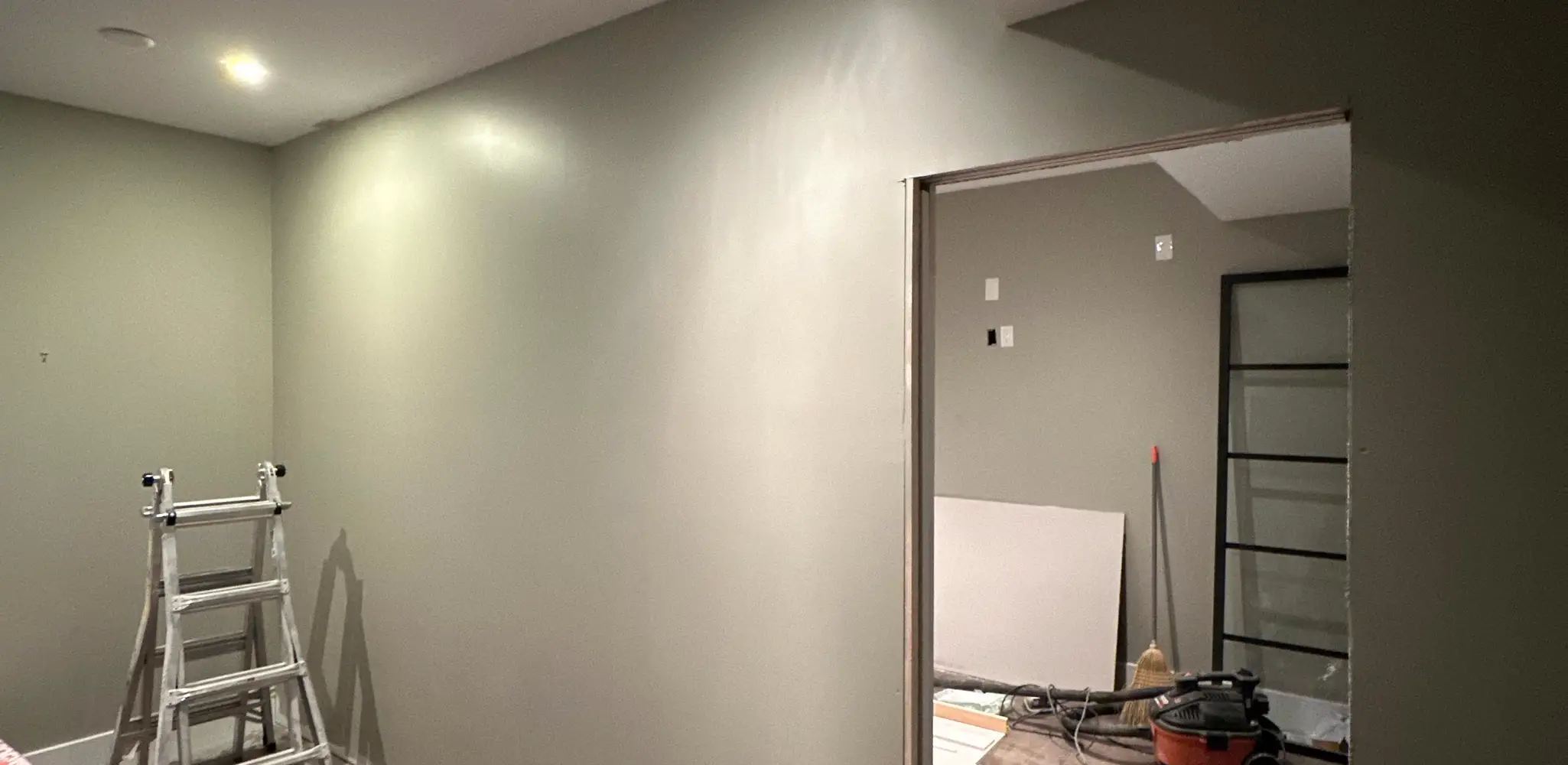 A living room under renovation with bare walls and tools, whole home remodel